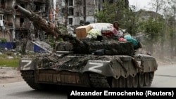 Російські танкісти з побутовими речами, які, за словами вимушеної переселенки Аліни Коренюк, були викрадені з її будинку. Луганська область, Україна, 26 травня 2022 року